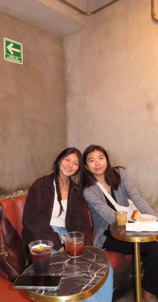 Two teammates smiling over iced coffees at a café in Mexico City