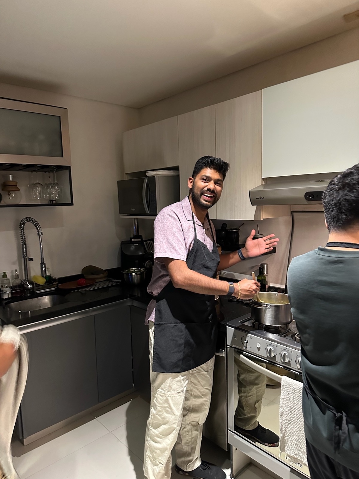 A teammate in an apron laughing while cooking at the stove