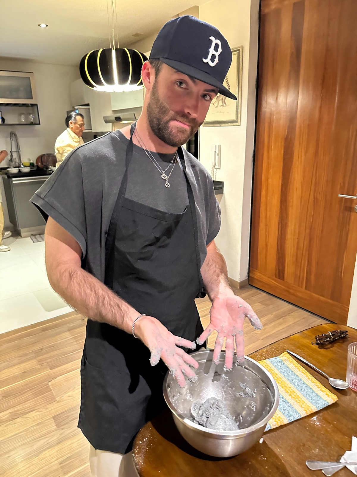 A teammate in an apron mixing masa by hand in a metal bowl