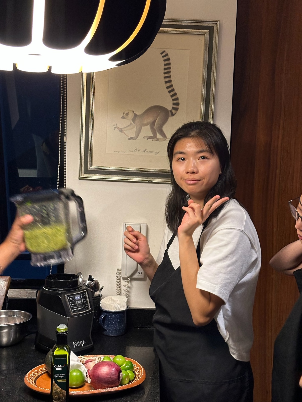 A teammate in an apron next to a blender full of green salsa in the kitchen