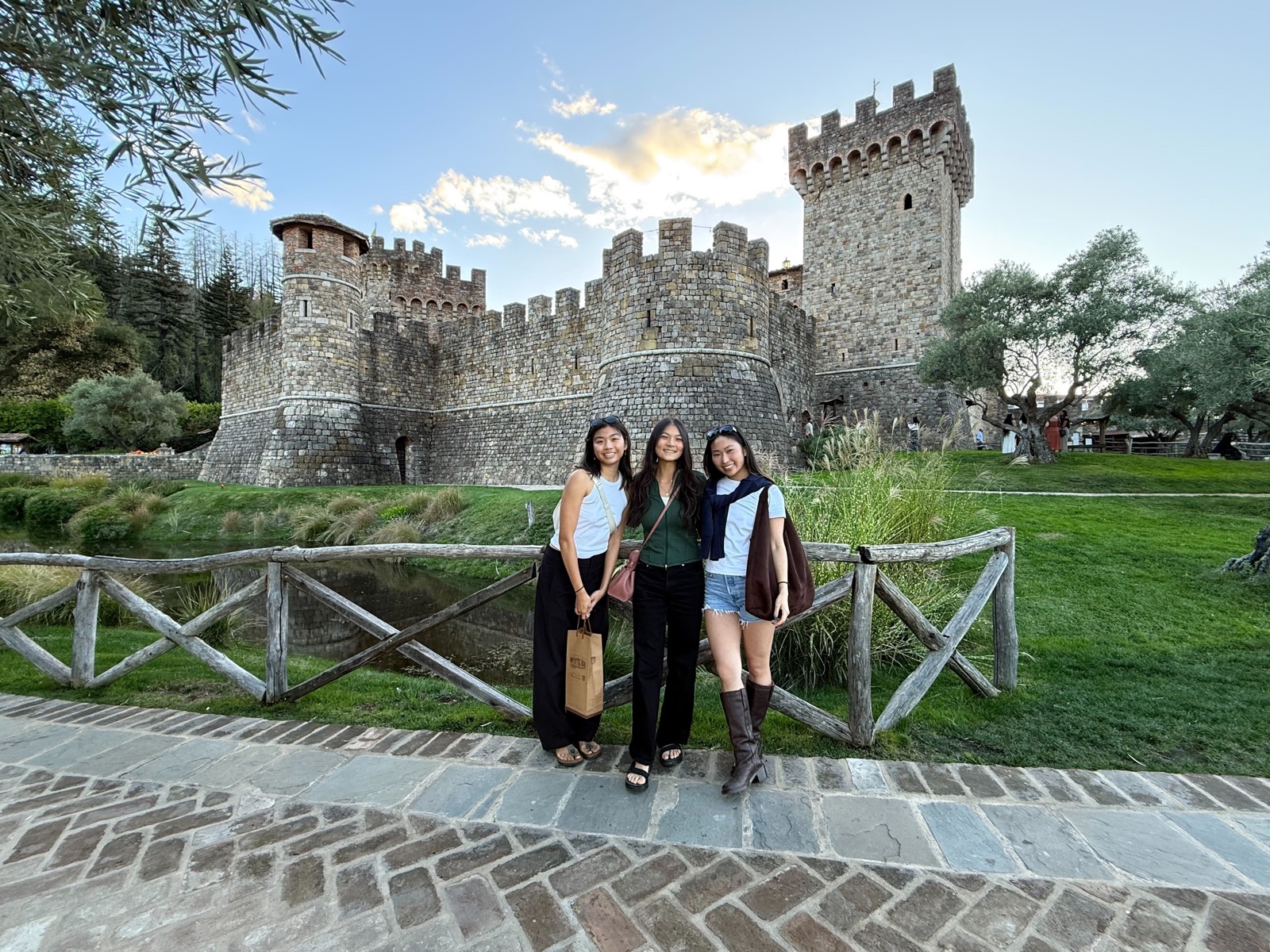 Three teammates posing in front of a stone castle at golden hour