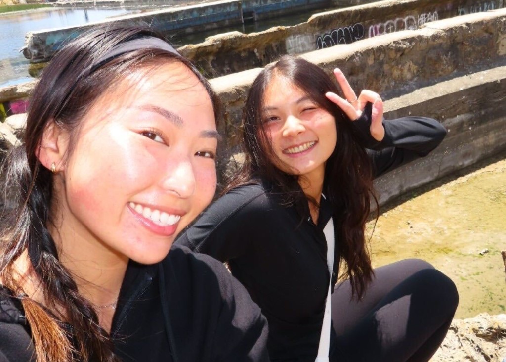 Two teammates taking a sunny selfie with a peace sign at the Lands End ruins