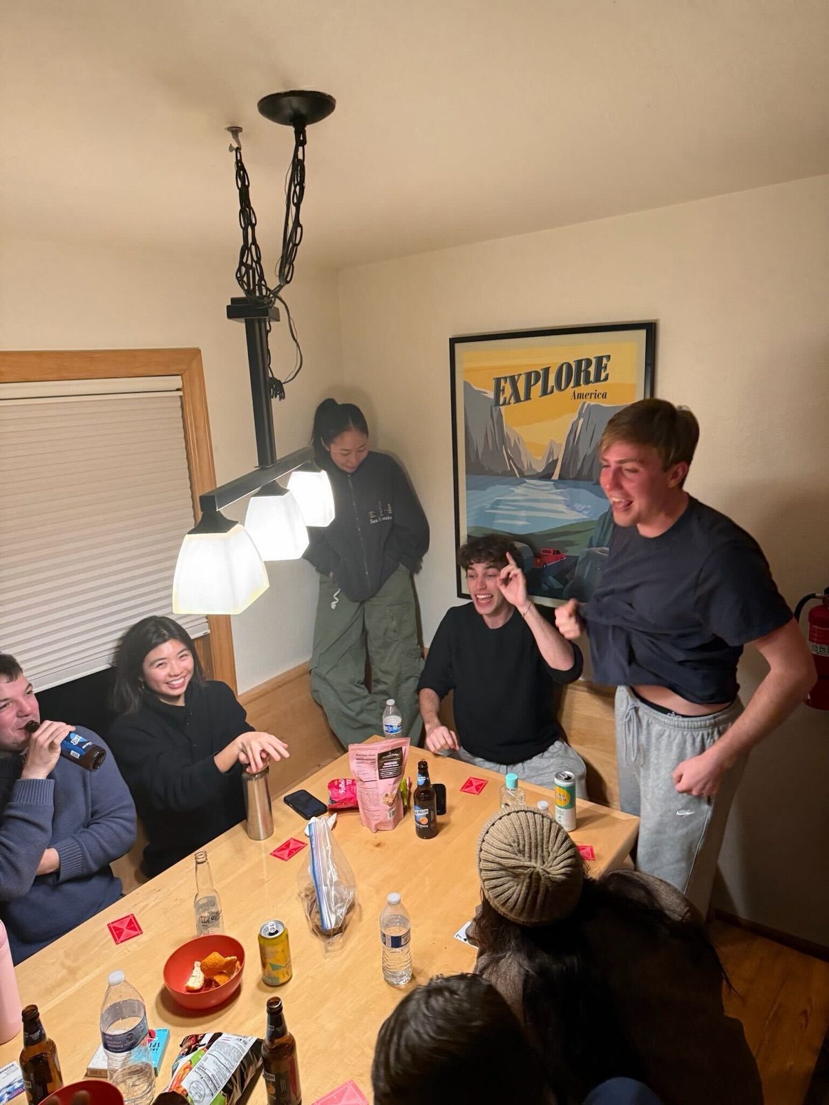 Teammates laughing over card games and drinks at a cabin table