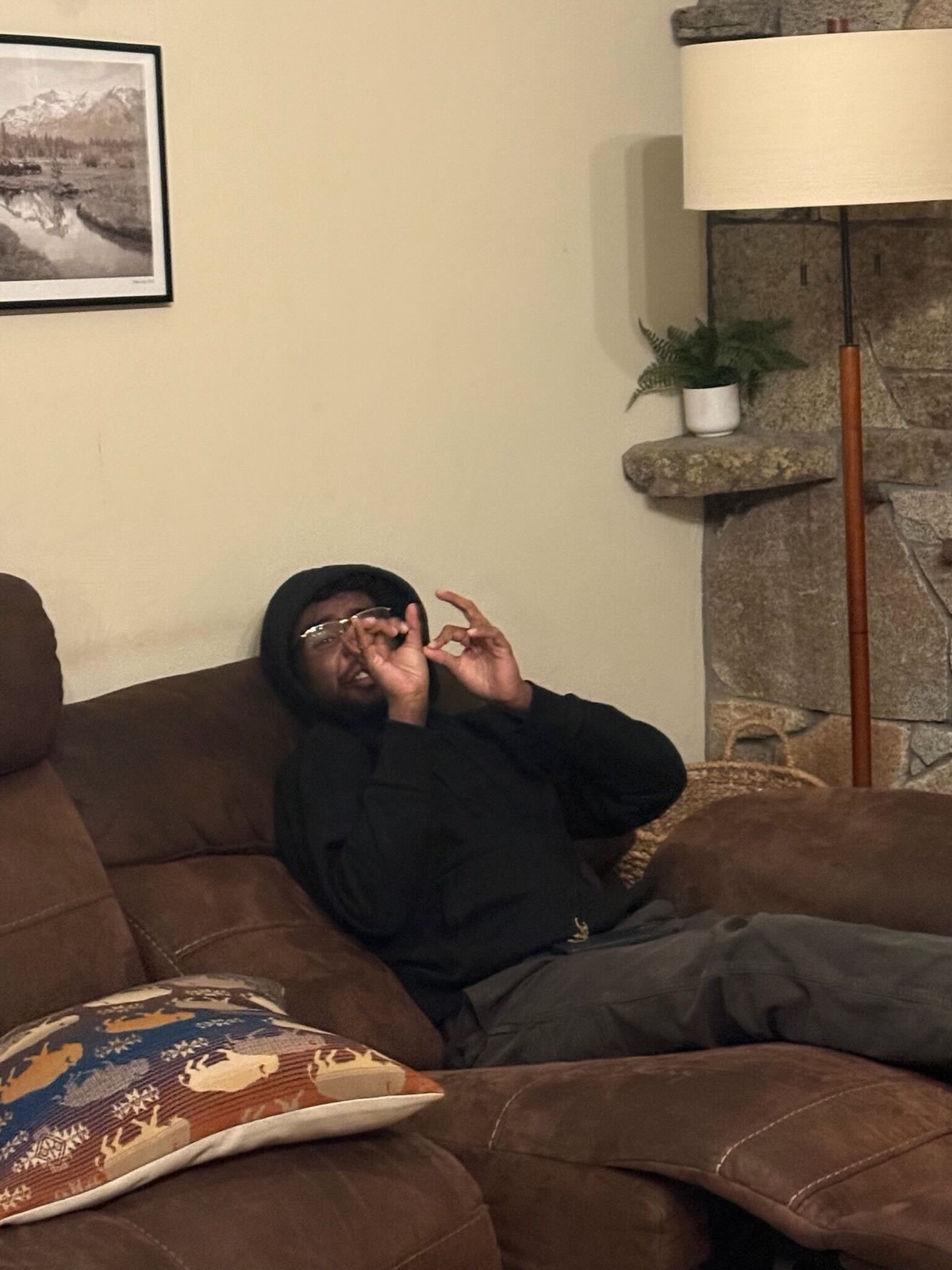 A teammate sprawled on a cabin couch throwing up a peace sign after a long day