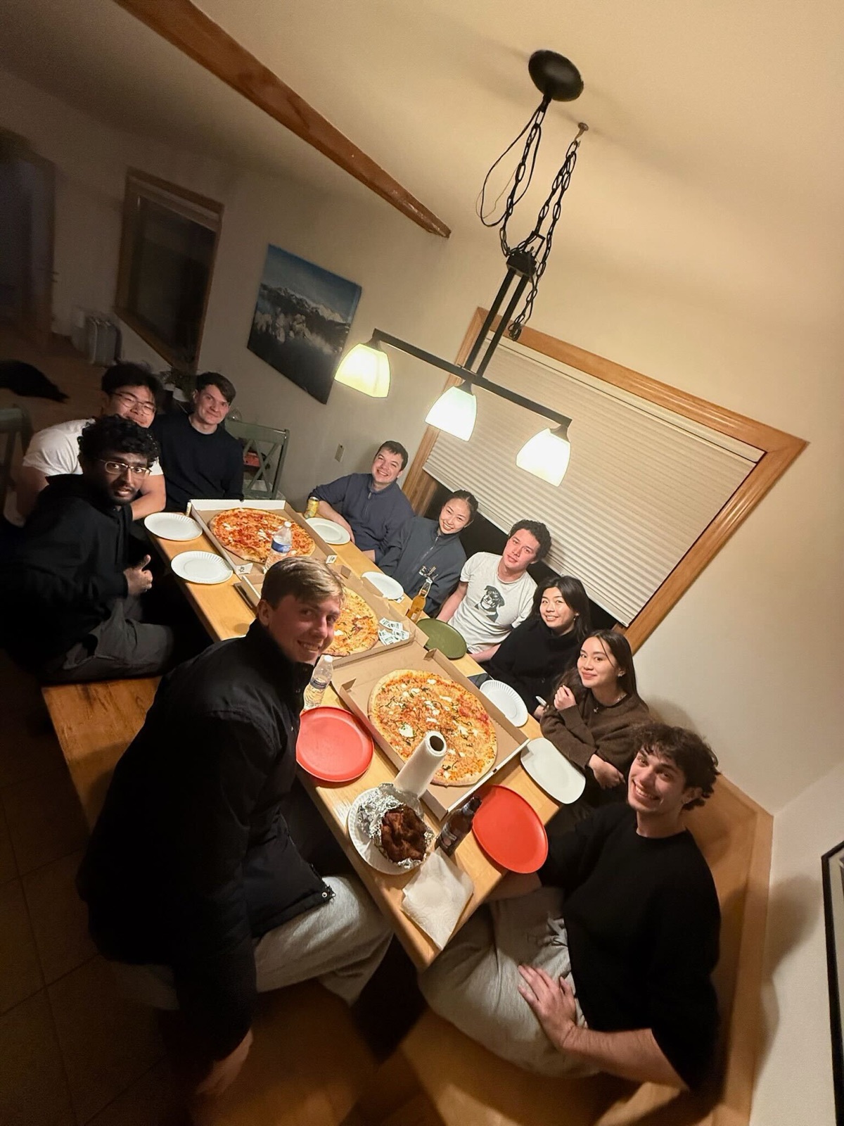 The team crowded around a cabin dinner table covered in pizzas