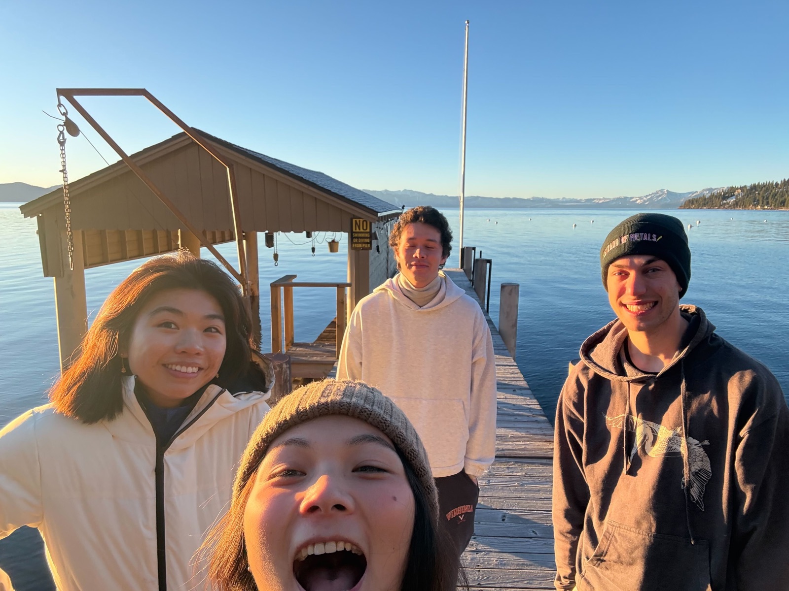 Four teammates on a lakeside dock at sunset, Lake Tahoe glowing behind them