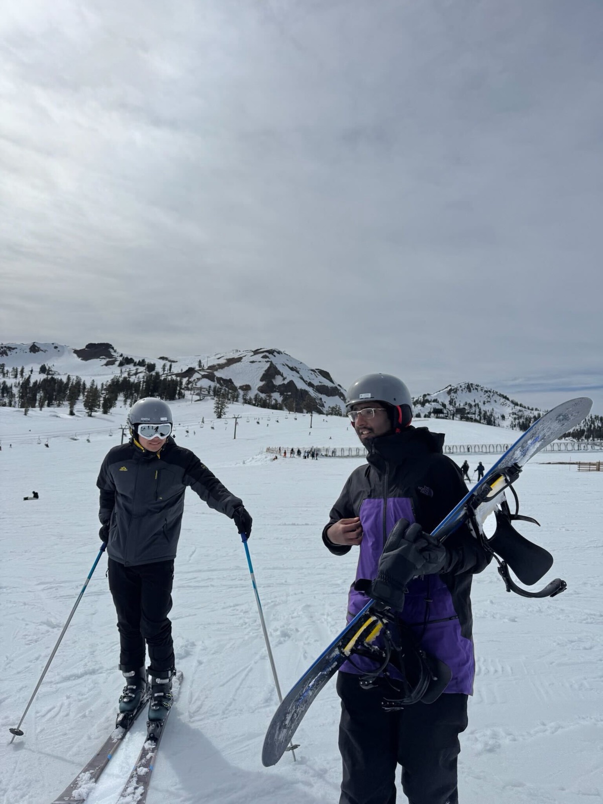 A skier and a snowboarder standing together on a snowy slope